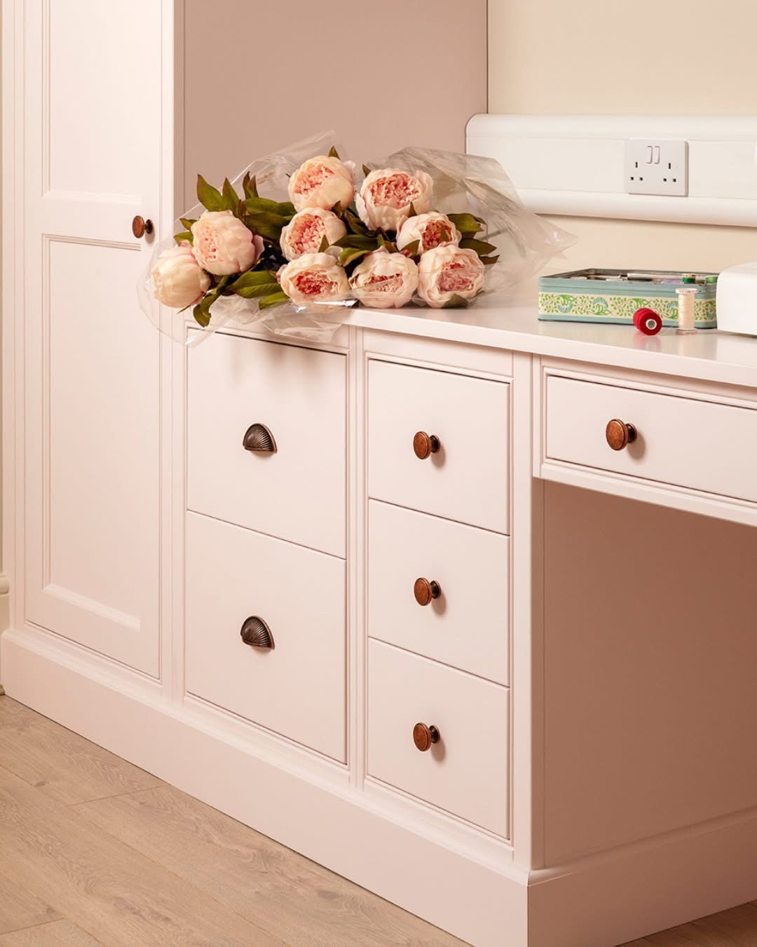 Blush pink fitted cabinetry with a stone worktop and bronze round handles