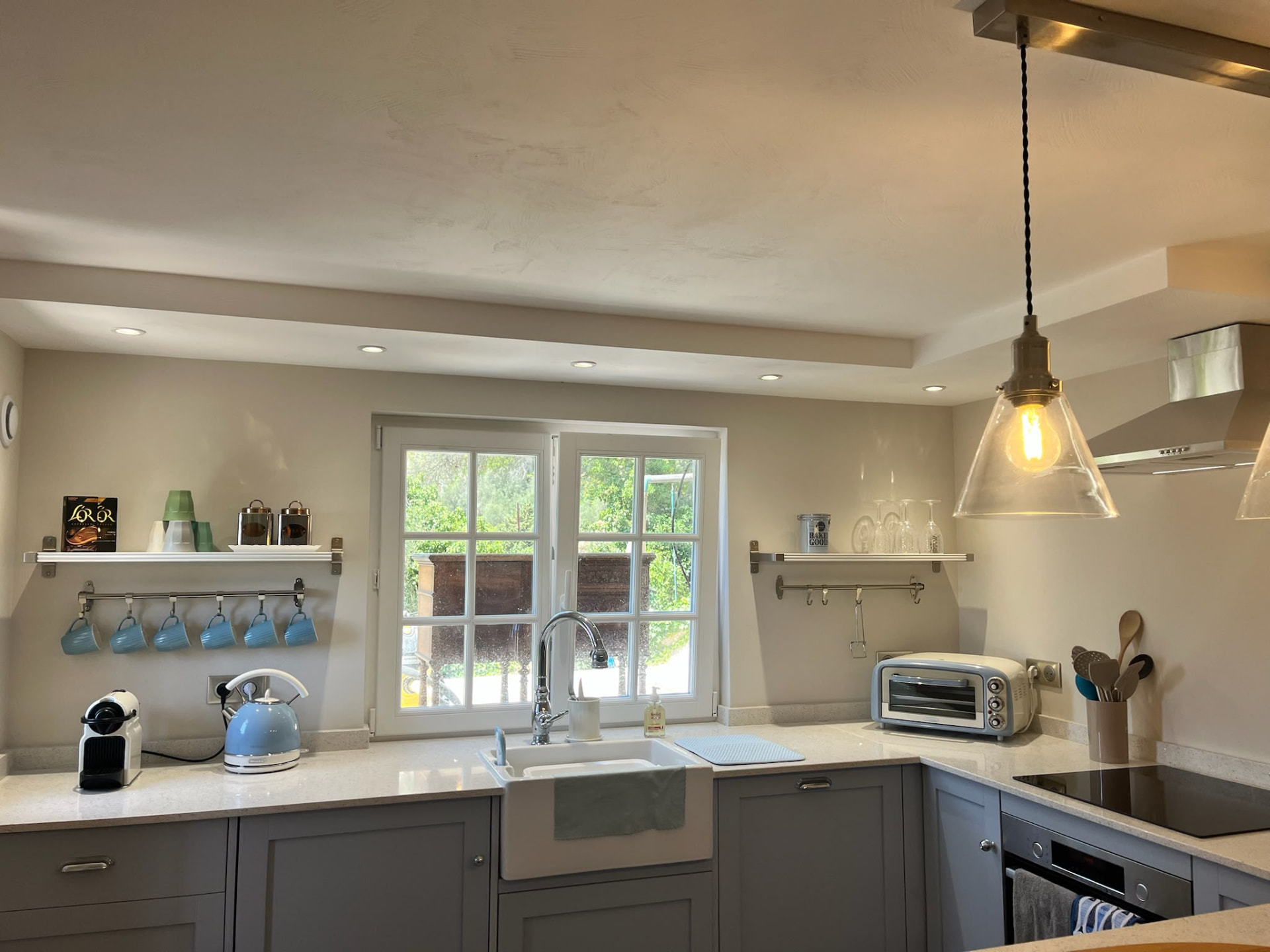 Blue-grey painted kitchen with shaker cabinets, an apron sink and worktop storage