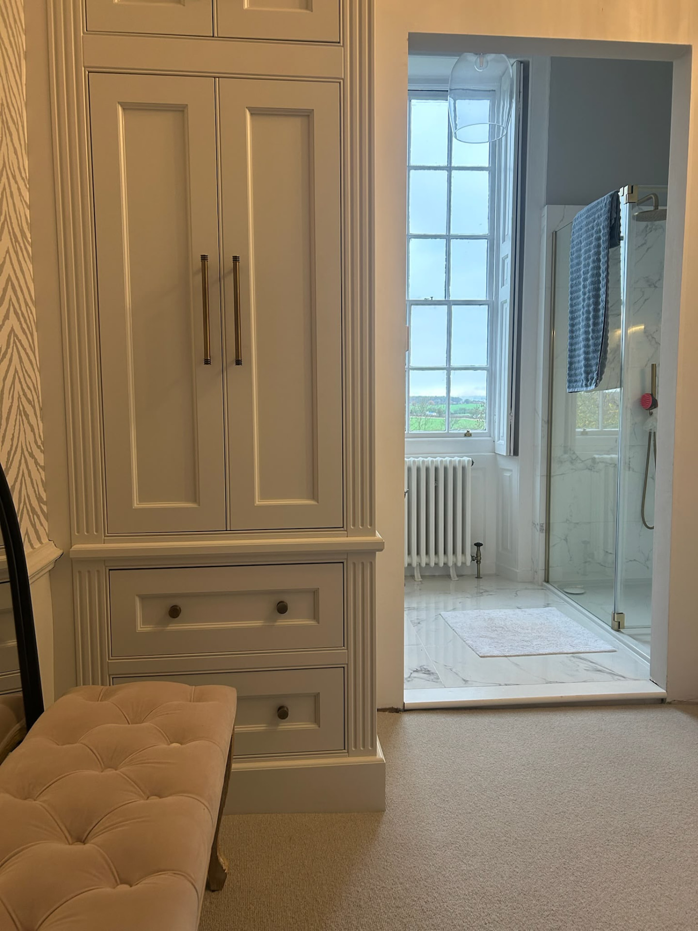 Tall cream fitted wardrobe tower with fluted pilasters, brass handles and lower drawers