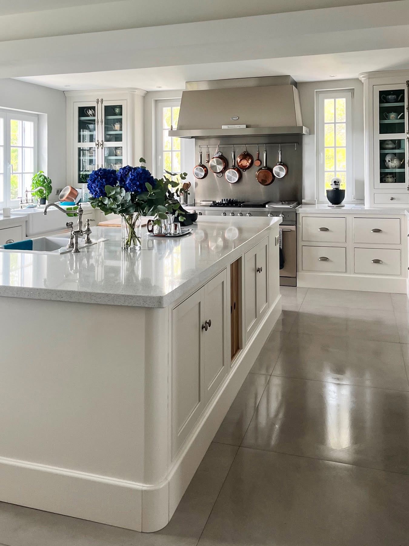 White painted kitchen in Monaco with a curved island, stone worktop and range cooker